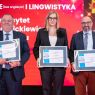 zdjęcie: grupa trojga osób pozuje do zdjęcia, trzymając w dłoniach dyplomy