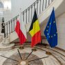 Flagi: Polski, Belgii i Unii Europejskiej na tle zabytkowych schodów