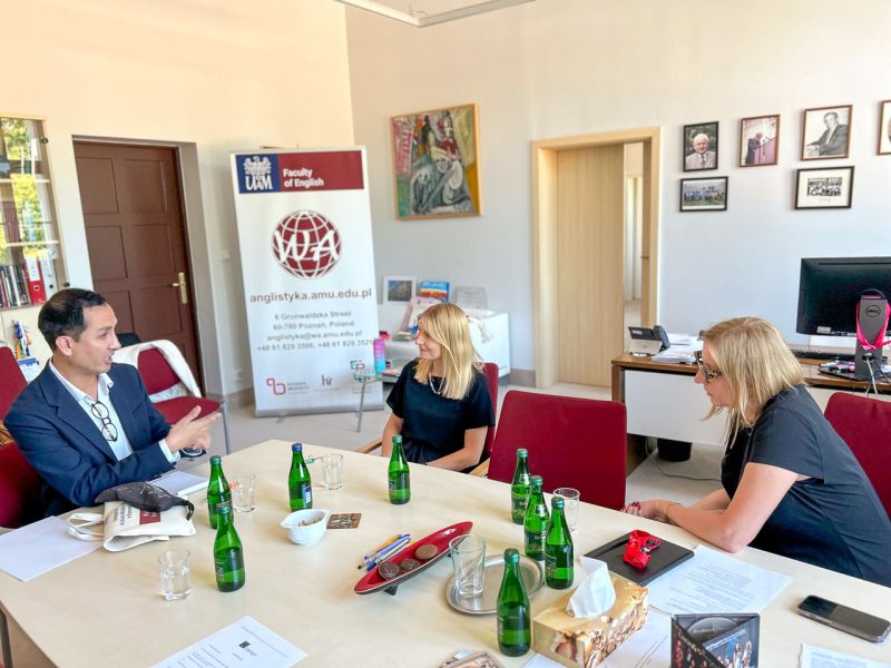 zdjęcie: trzy osoby siedzą przy stole w biurze, prowadząc rozmowę