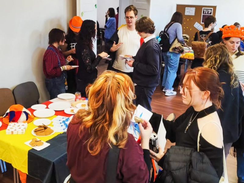 zdjęcie: grupa osób w sali seminaryjnej, stół z ulotkami, tacami z waflami i innymi przekąskami