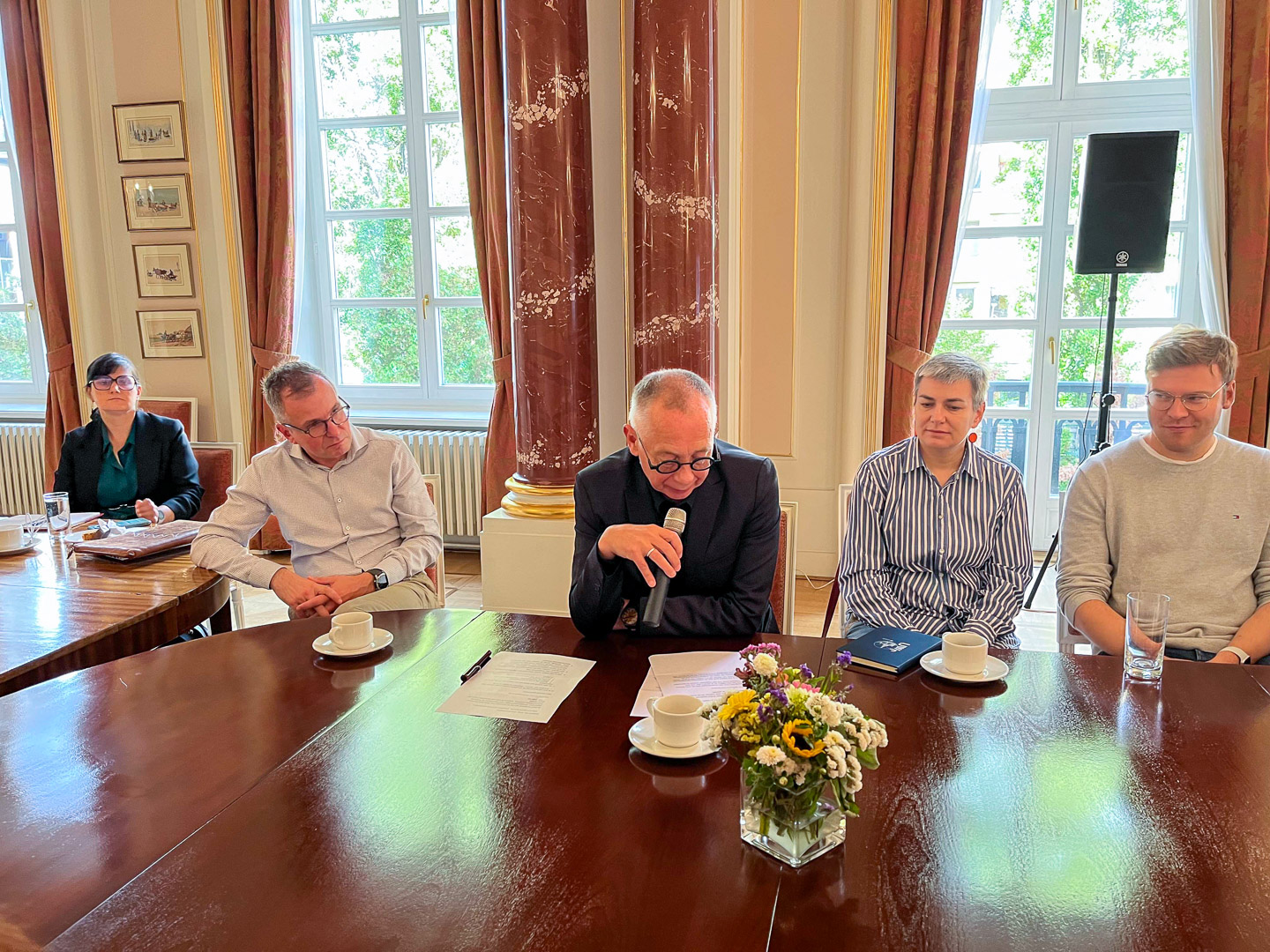 Martin van Dijk siedzi przy stole i mówi do mikrofonu