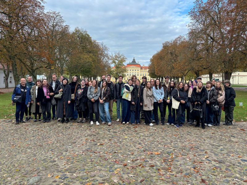 zdjęcie: grupa osób pozuje przed pałacem