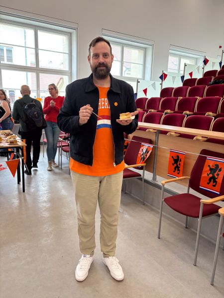 zdjęcie: dr Mikołaj Buczak prezentuje w stronę obiektywu słodkości przygotowane dla uczestniczących w wydarzeniu