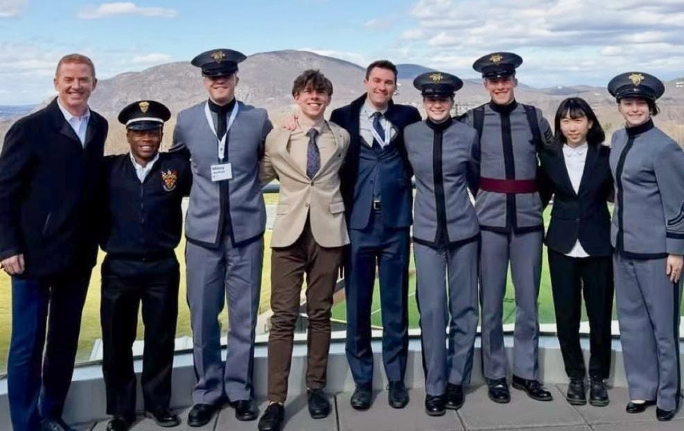 photograph: a group of nine people, four of them dressed in uniform, pose for a photograph in the open