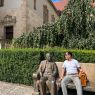 photograph: a person poses for a photograph on a bench in front of a building