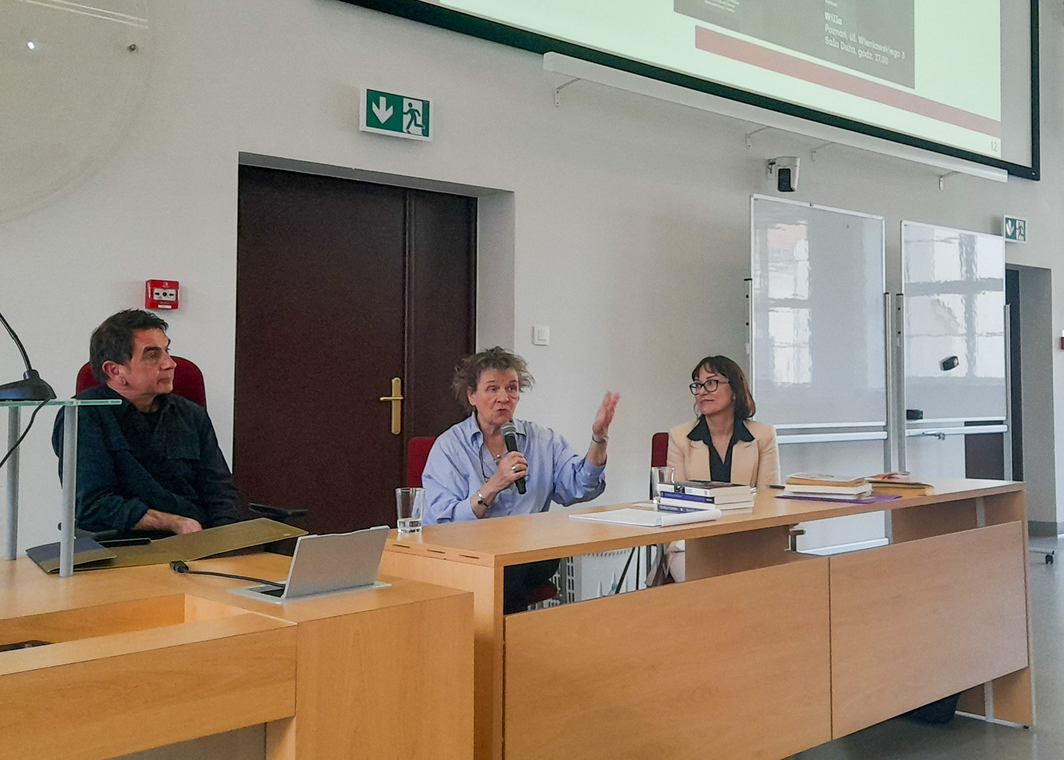 photograph: three persons sitting behind a desk in a lecture hall