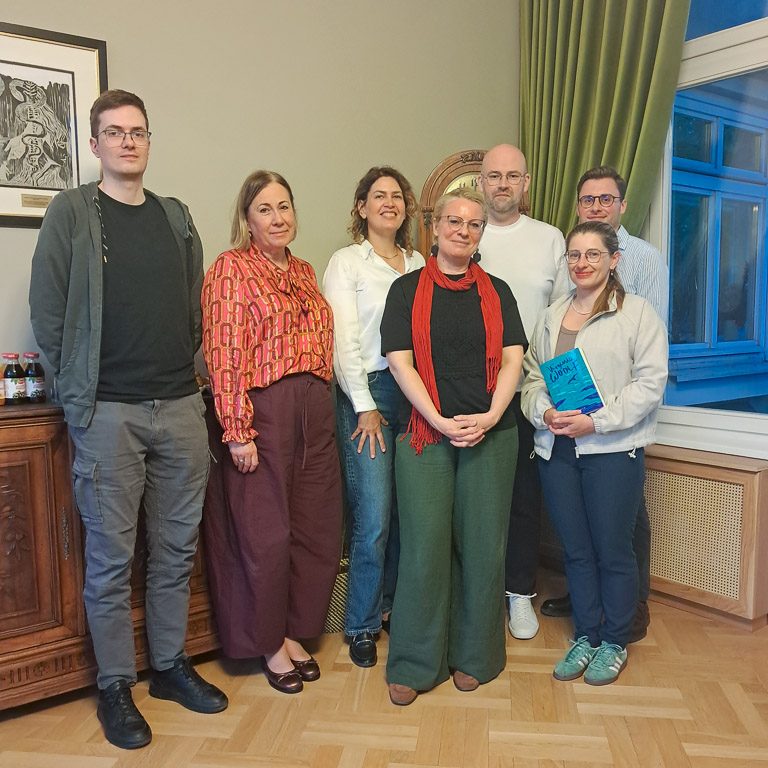 zdjęcie: grupa siedmiu osób stoi jedna blisko drugiej, wszyscy patrzą w kadr