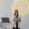 photograph: person with a microphone in hand addresses the audience (who are out of frame)