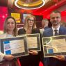 zdjęcie: grupa trojga osób pozuje do zdjęcia, trzymając w dłoniach dyplomy