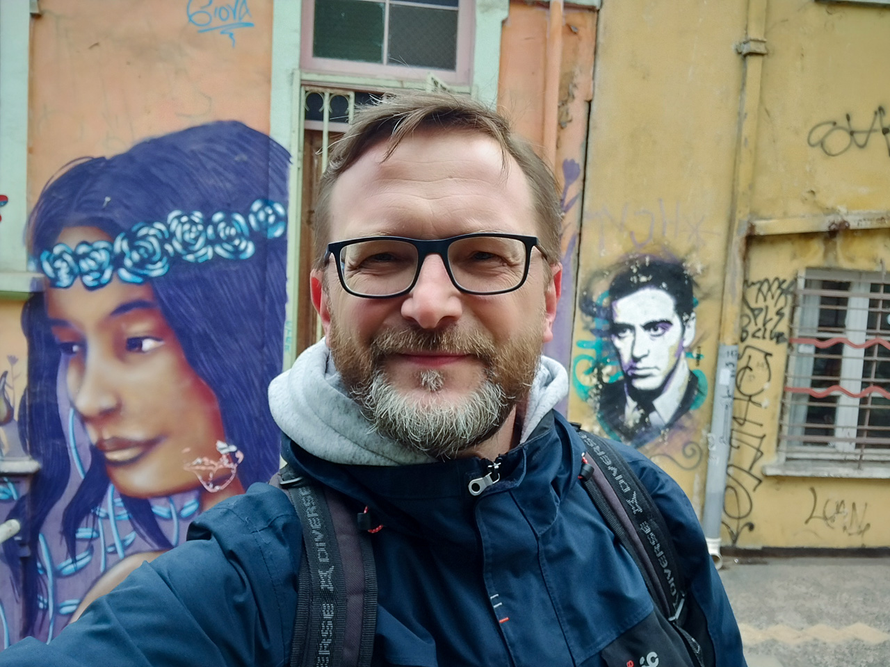 zdjęcie: osoba pozuje do zdjęcia na tle murali
