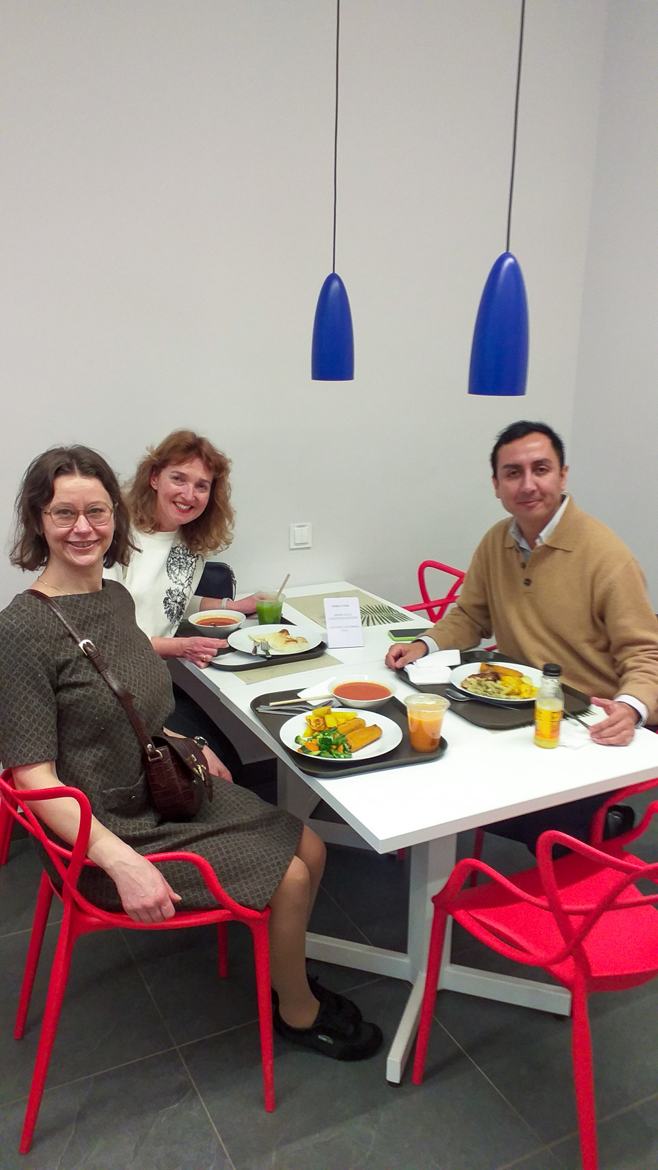photograph: three persons pose for a photograph by a café table