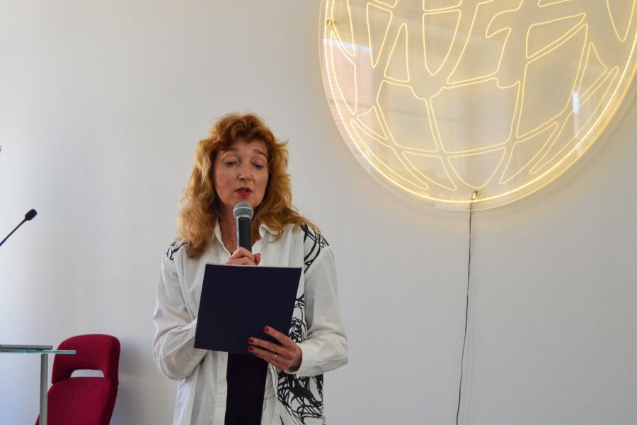 photograph: person with a microphone in hand addresses the audience (who are out of frame)