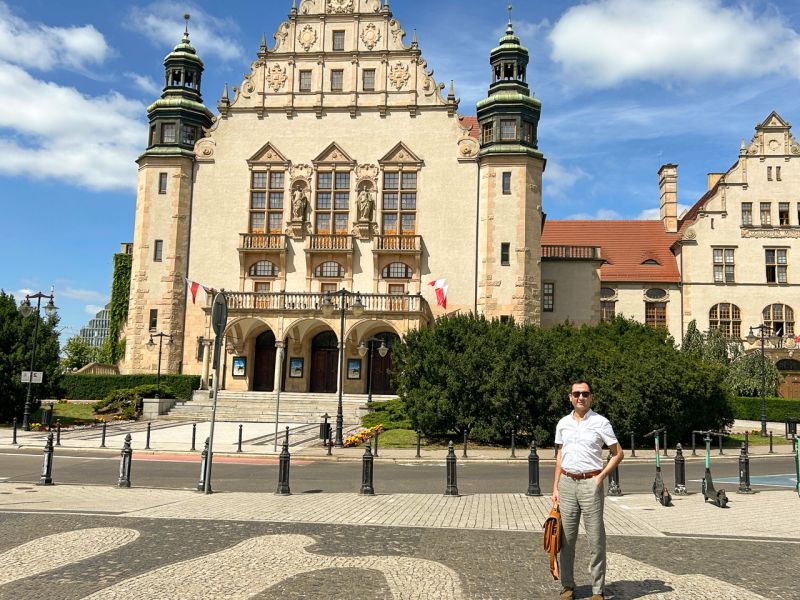 zdjęcie: osoba pozuje do zdjęcia przed gmachem