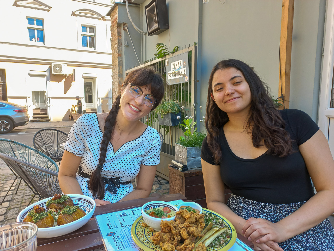 photograph: two persons pose for a photograph by a café table