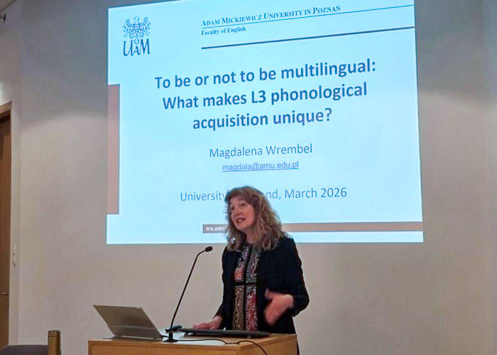 photograph: Prof. Magdalena Wrembel behind the pulpit in a seminar room; on the screen behind her is the title slide of the slide show