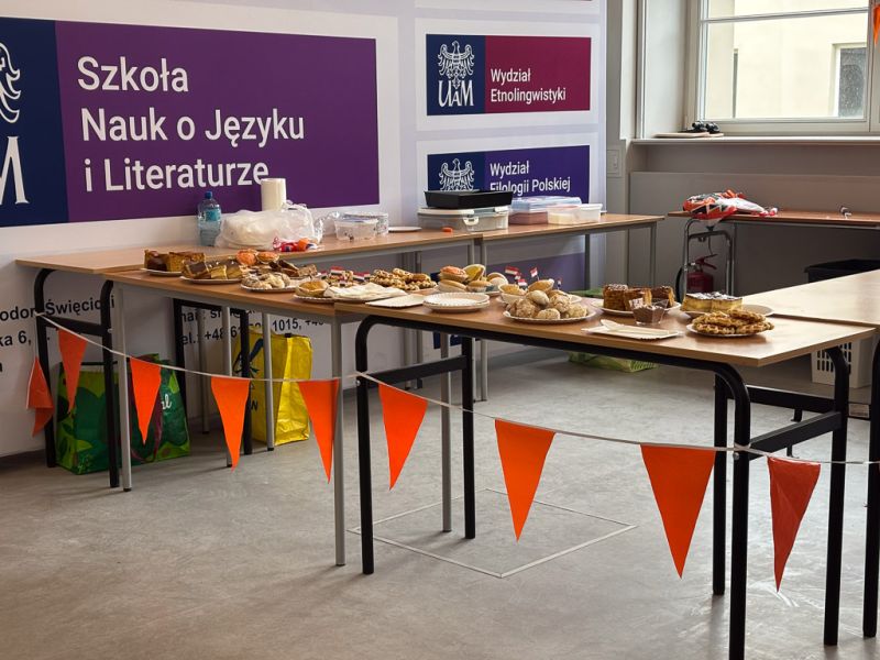 zdjęcie: aula: stoły zastawione słodkościami oraz udekorowane pomarańczowymi chorągiewkami
