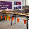 zdjęcie: aula: stoły zastawione słodkościami oraz udekorowane pomarańczowymi chorągiewkami