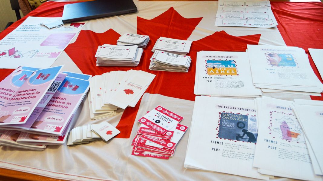 zdjęcie: stół zastawiony ulotkami i innymi materiałami promocyjnymi; wśród nich flaga Kanady