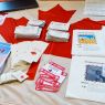 zdjęcie: stół zastawiony ulotkami i innymi materiałami promocyjnymi; wśród nich flaga Kanady