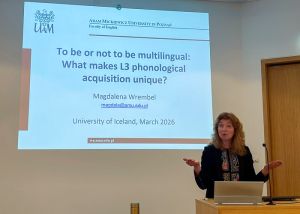 photograph: Prof. Magdalena Wrembel behind the pulpit in a seminar room; on the screen behind her is the title slide of the slide show
