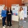 photograph: three persons pose next to conference poster stands