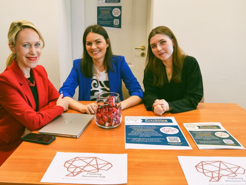 zdjęcie: grupa trzech osób pozuje przy stole z materiałami promocyjnymi