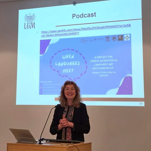 photograph: Prof. Magdalena Wrembel behind the pulpit in a seminar room; on the screen behind her is on of the slides of the slide show