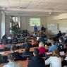 zdjęcie: wykład akademicki w sali, prelegenci przy katedrze i publiczność