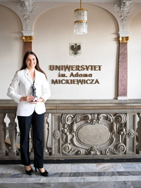 photograph: person poses for a photograph holding a diploma and a statuette