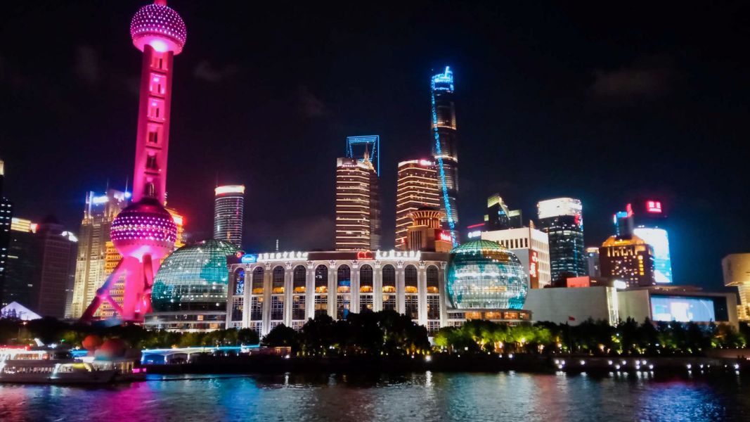 photograph: cityscape: a night sky, buildings lit with colourful electric lights, and a river