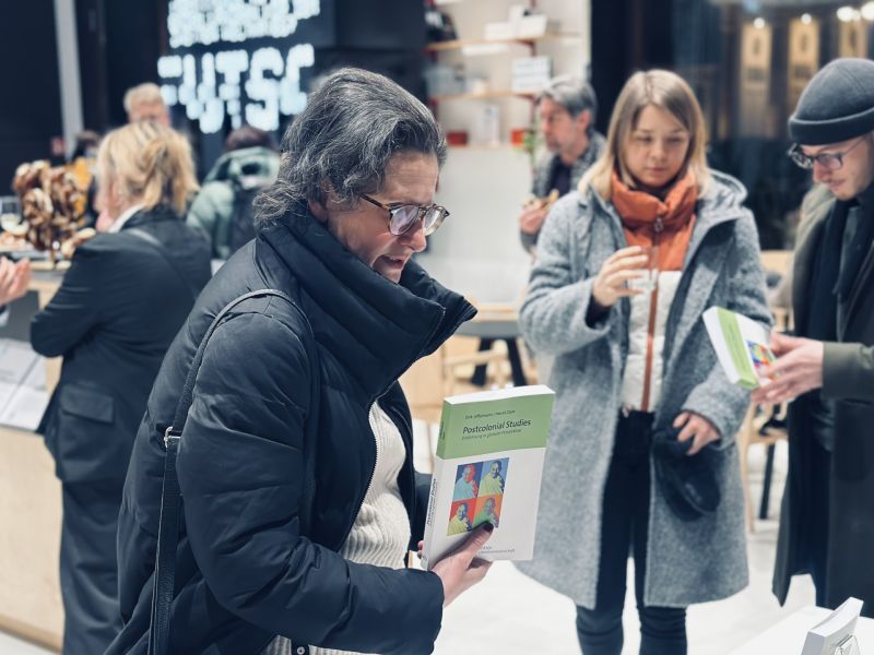 zdjęcie: osoba trzymająca egzemplarz książki „Postcolonial Studies” podczas rozmów w przestrzeni wydarzenia