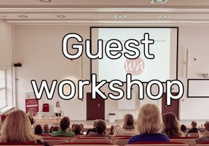 Photograph: audience in a lecture hall; caption: Guest workshop