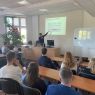 zdjęcie: wykładowca wskazujący slajd na ekranie podczas wykładu
