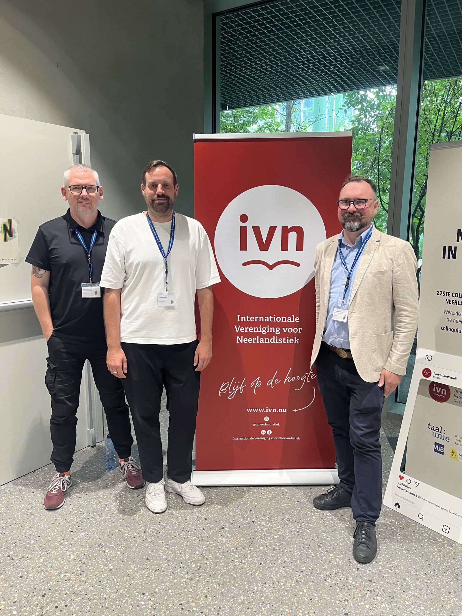 Trzech panelistów z UAM na tle logo IVN-u