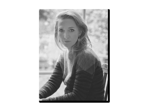 Osoba siedząca przy oknie w czarno‑białym ujęciu, w swetrze o geometrycznym wzorze