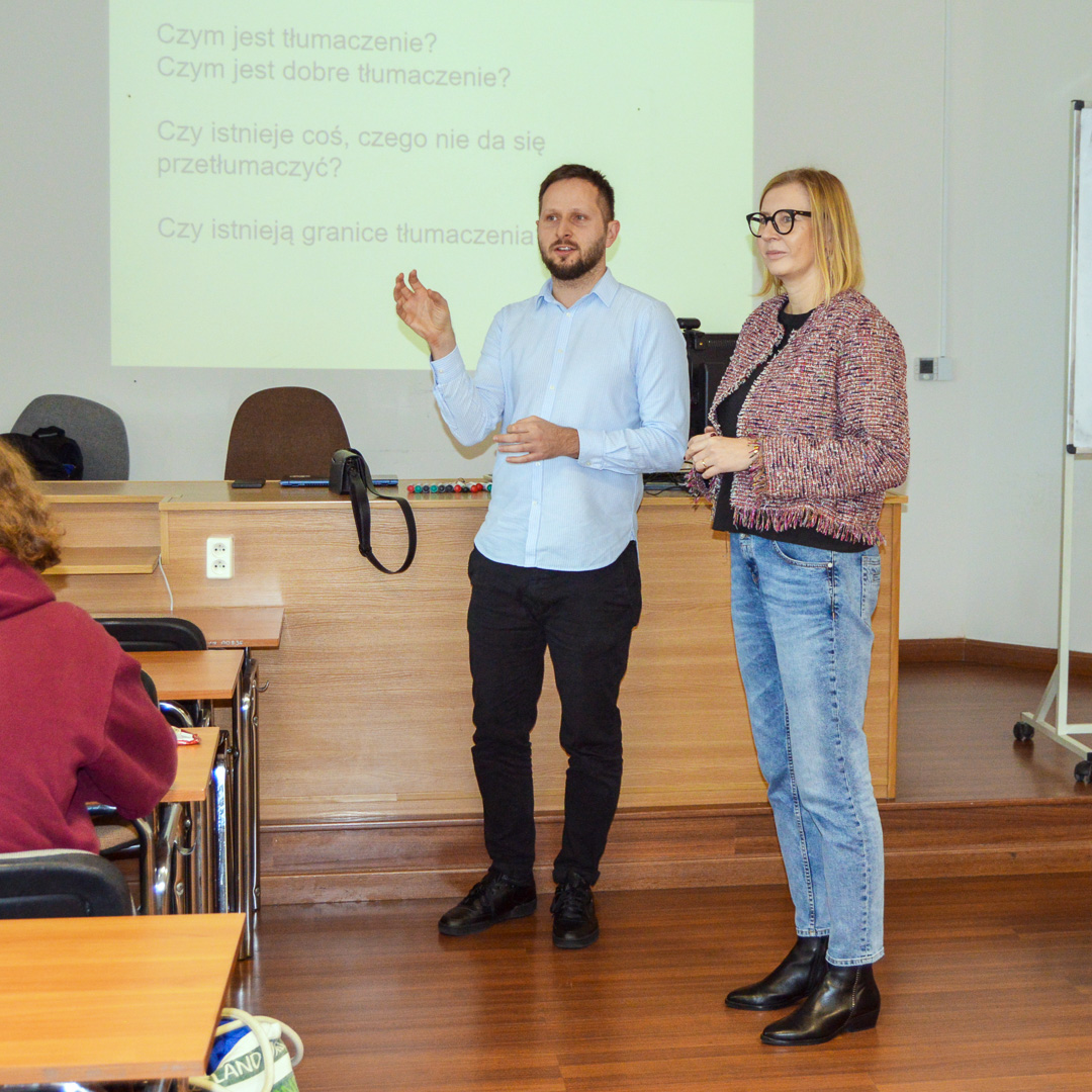 zdjęcie: dwoje prowadzących warsztat lub wykład oraz publiczność w sali seminaryjnej, w tle ekran z obrazem z rzutnika