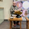 Zdjęcie przedstawiające siedzącego przy stoliku prof. Jerzego Kocha wyjmującego kartki z żółtej teczki