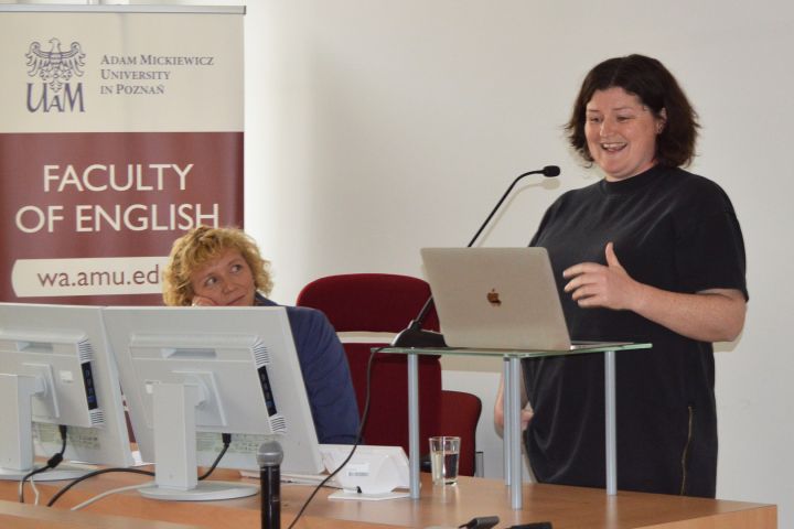 photograph: a person addresses the audience from behind the pulpit; another person looks at the speaker
