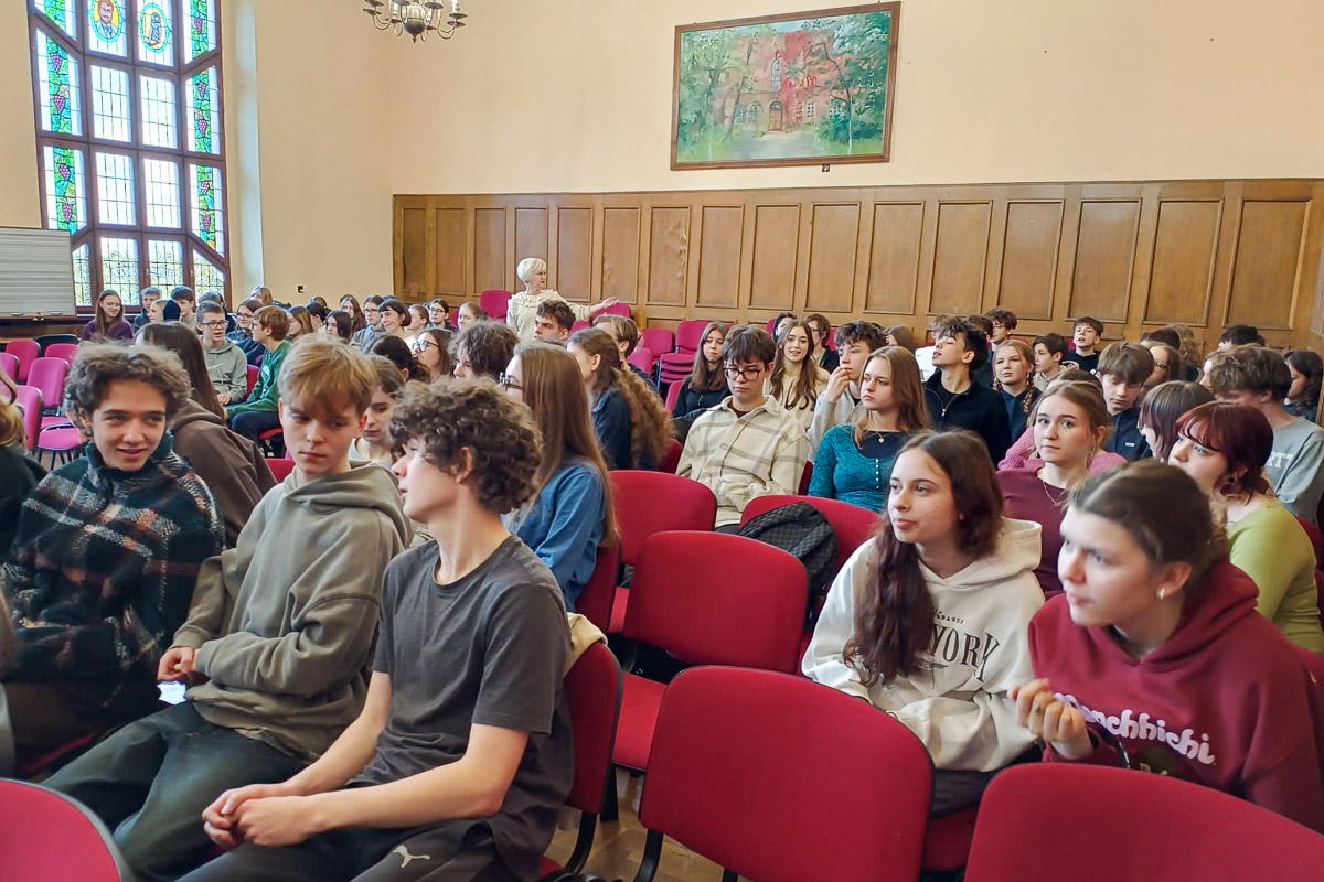 zdjęcie: gruoa kilkudziesięciu osób siedzi na krzesłach ustawionych w dobrze oświetlonej sali