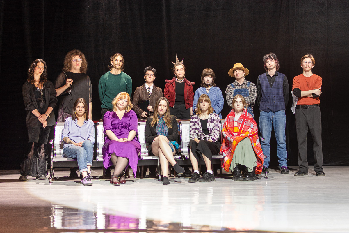 zdjęcie: czternaście ośób pozuje na scenie teatru, dziewięć stoi, pięć siedzi