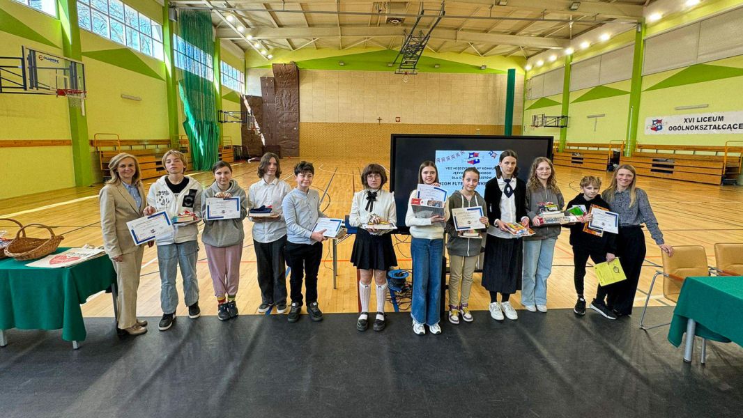 zdjęcie: sala gimnastyczna; grupa trzynastu osób pozuje, stojąc; wszystkie oprócz jednej trzymają w rękach dyplomy