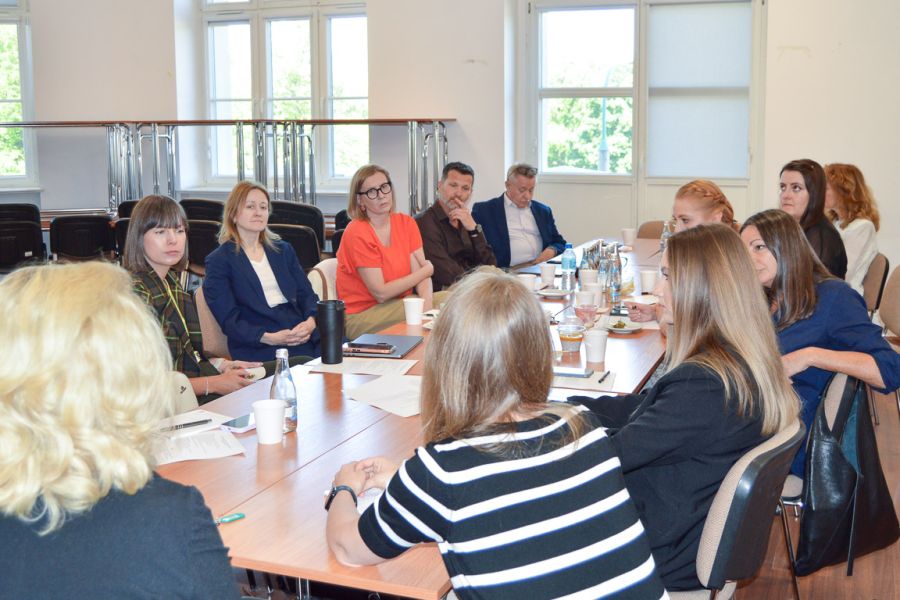 photograph: group of a dozen or so people are having a discussion, seated around a block of desks in a seminar room