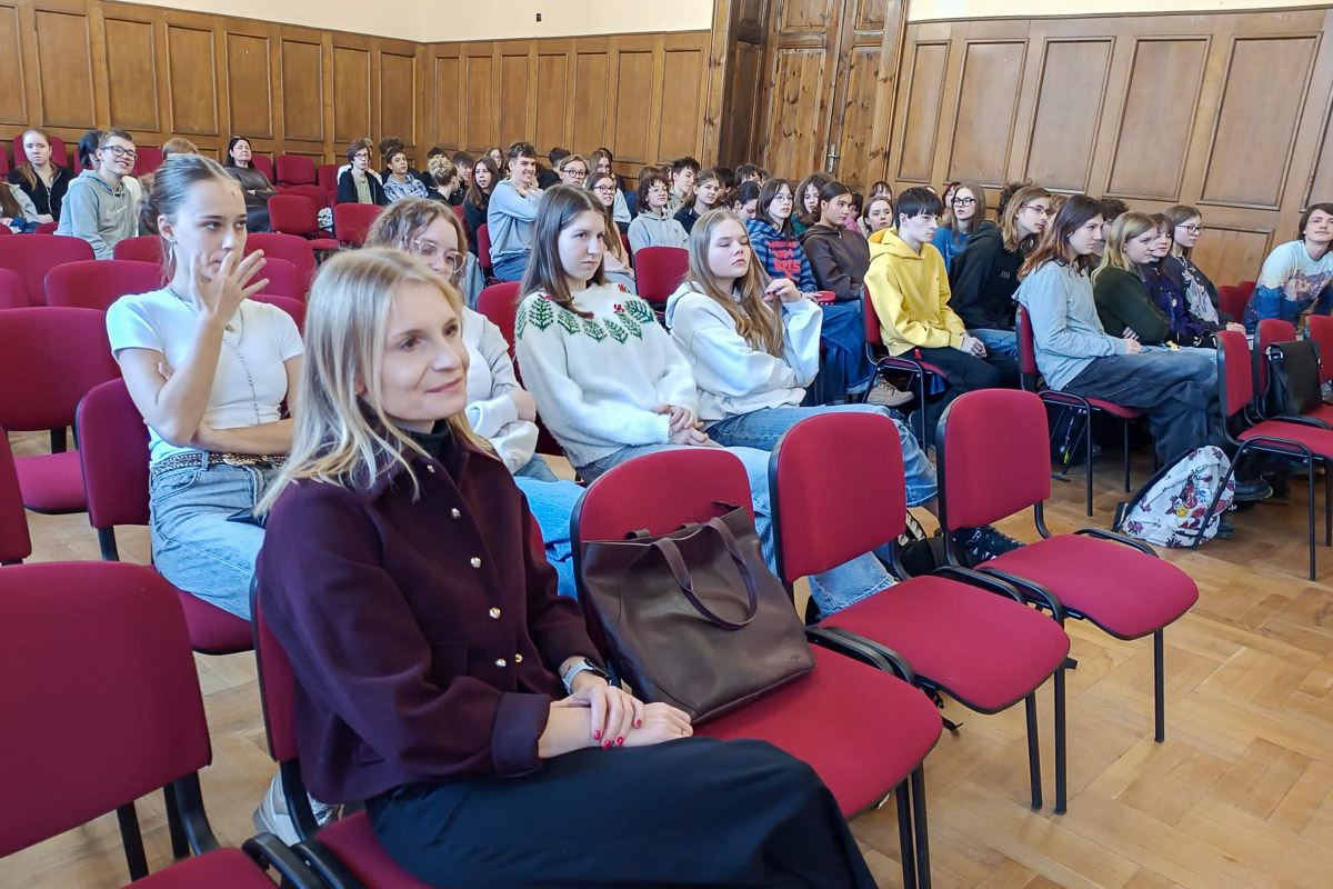 zdjęcie: gruoa kilkudziesięciu osób siedzi na krzesłach ustawionych w dobrze oświetlonej sali