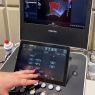 photograph: an ultrasound device in a laboratory; someone’s fingers point to the machine settings buttons