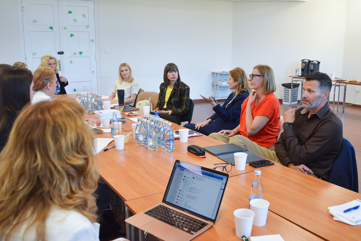 photograph: group of a dozen or so people are having a discussion, seated around a block of desks in a seminar room