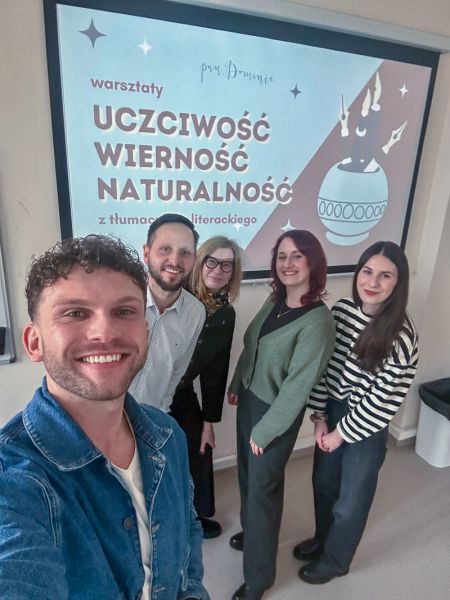 zdjęcie: pięcioro osób pozuje przed ekranem z wyświetlonym slajdem z prezentacji