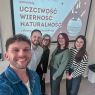 zdjęcie: pięcioro osób pozuje przed ekranem z wyświetlonym slajdem z prezentacji