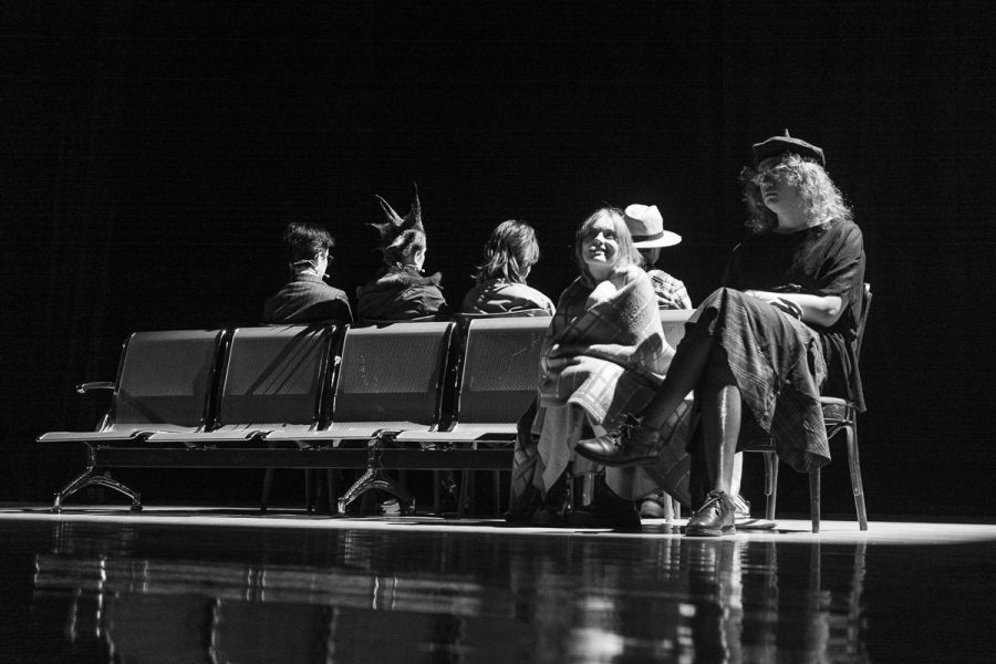 photograph: six people on a stage in a theatre during a rehearsal; four face away from the camera, two face the camera