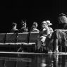 photograph: six people on a stage in a theatre during a rehearsal; four face away from the camera, two face the camera