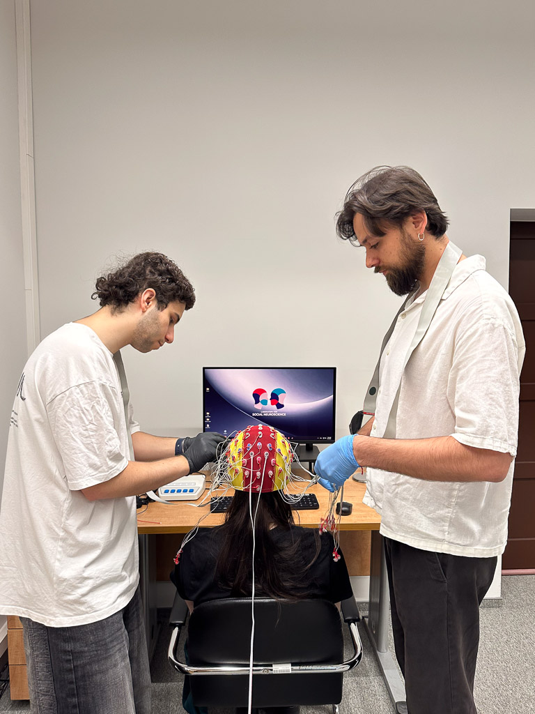 photograph: two persons readying an electroencephalograph for an experimant